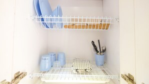 Een keuken met witte planken met servies, bekers en bestek.