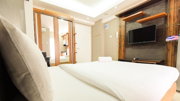 Een hotelkamer met een groot bed, een aan de muur bevestigde televisie en een houten garderobe.