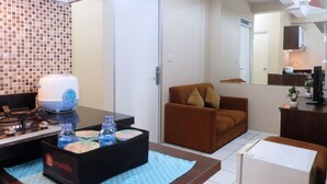 Habitación de hotel con cocina, sofá y mesa de comedor con una caja de artículos de tocador.