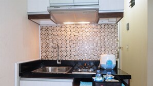 Una cocina compacta con estufa a gas, un lavamanos y un salpicadero de azulejos.