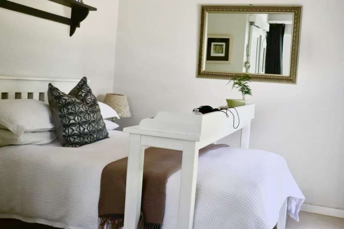 Ein Schlafzimmer mit Bett, Nachttisch und Spiegel an der Wand.