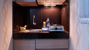 A compact kitchen with a gas stove, sink, and a small countertop area. - Warm Cozy Menteng Square Apartment (Jakarta)