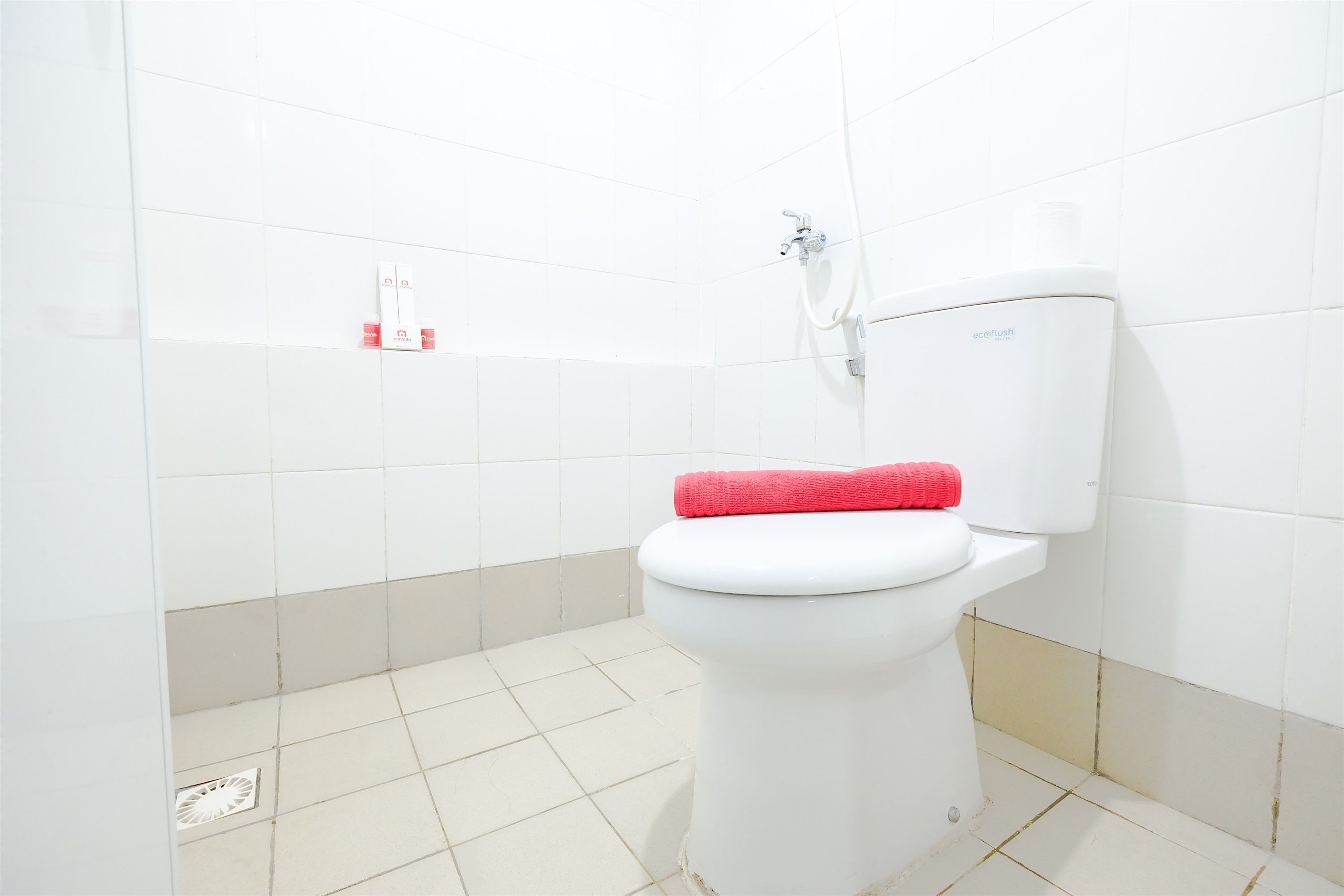 A bathroom with a white toilet, a showerhead, and a tiled floor.
