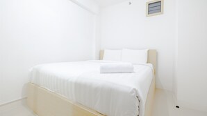 A minimalist bedroom with a single bed, white walls, and a small window. - Simply & Clean Bassura City Apartment (Jakarta)