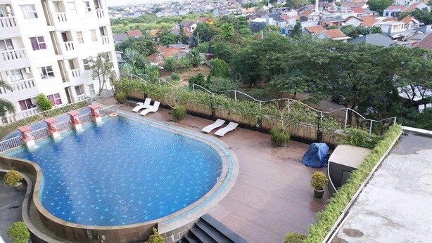 Une piscine sur le toit, dotée de chaises longues et offrant une vue sur le quartier environnant.
