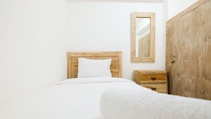 A minimalist bedroom with a wooden headboard, a white pillow, a wooden nightstand with drawers, and a large wardrobe.
