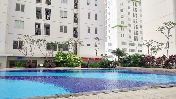 A swimming pool surrounded by a residential building with balconies and a visible shop sign.