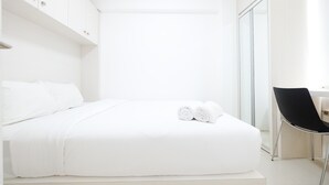Une chambre à coucher moderne et minimaliste, avec un lit soigneusement fait, une chaise noire et un dressing.