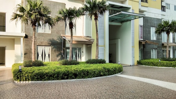 Un edificio moderno con un patio empedrado, palmeras y una entrada techada.