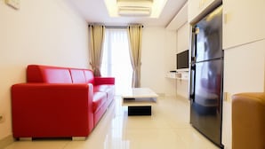 Una sala moderna con un sofá rojo, una mesa de centro blanca y un refrigerador negro.
