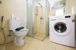 A bathroom with a toilet, a shower, and a washing machine. - The Wave Apartment near Kota Kasablanka (Jakarta)