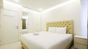 Un dormitorio ordenado con una cama grande, una mesita de noche y un armario.