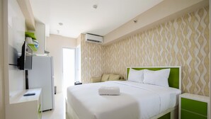 Ein modernes Hotelzimmer mit einem ordentlich bezogenen Bett, einem grünen Kopfteil und einer Wand mit Muster.