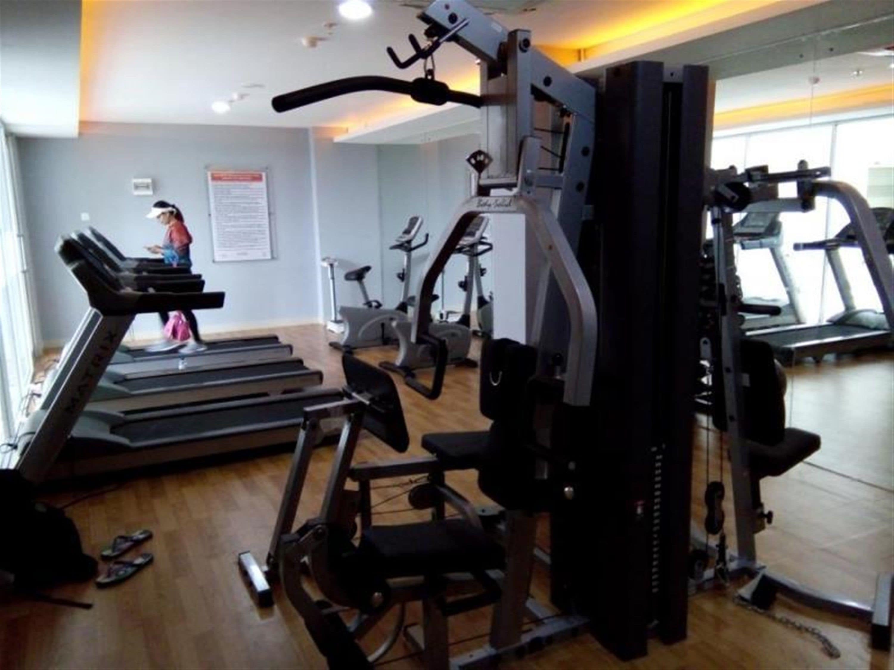 A gym with treadmills, a weight machine, and a mirror on the wall.