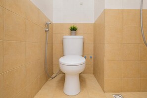 Ein kleines, kompaktes Badezimmer mit Toilette, Dusche und einer Topfpflanze an der Wand.