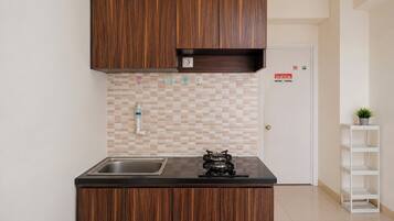 Una cocina funcional con armarios de madera, un lavamanos de acero inoxidable y un salpicadero de azulejos.