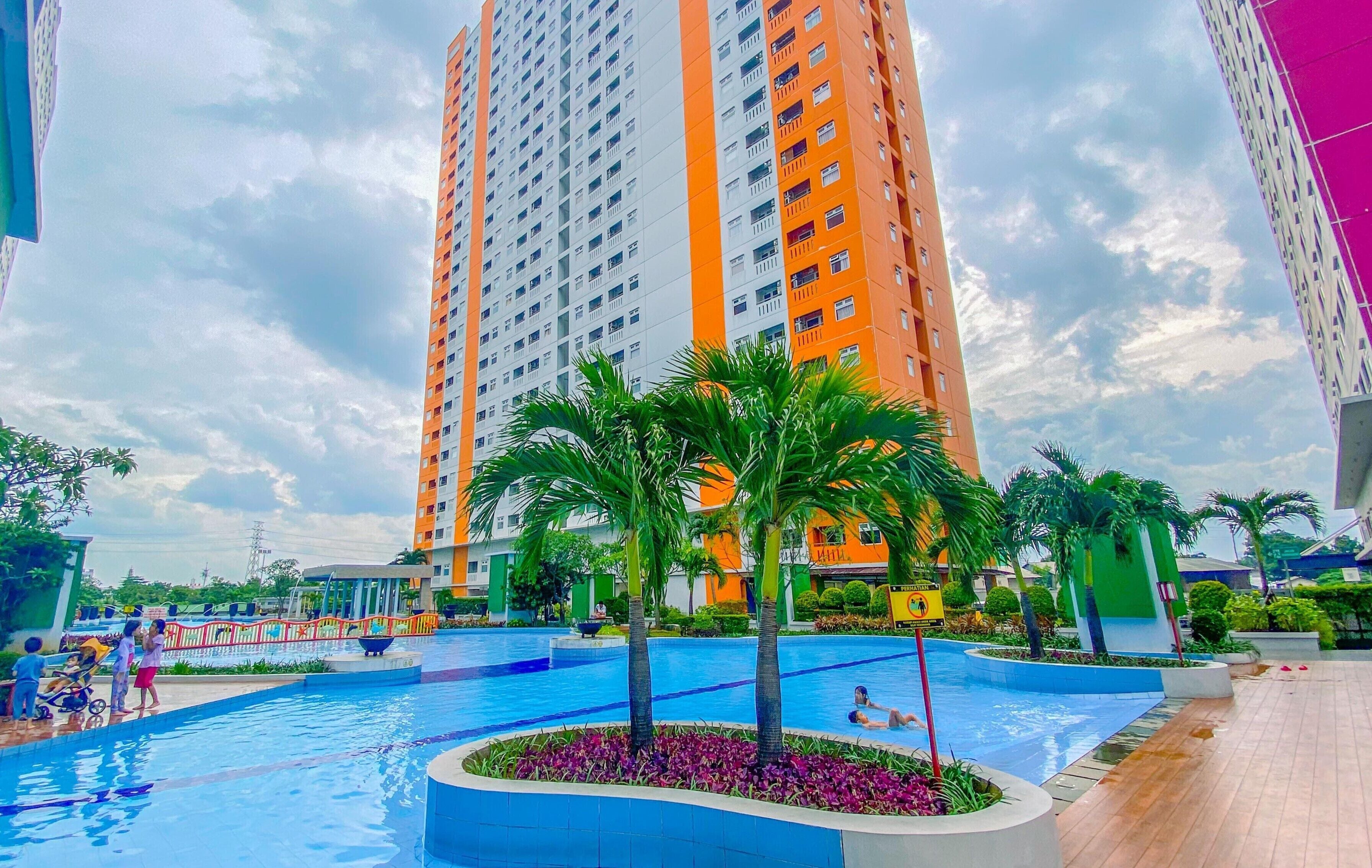 Una piscina rodeada de palmeras y un rascacielos al fondo.