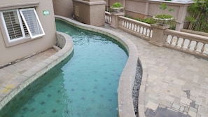 A swimming pool with a curved design, surrounded by a tiled walkway and a railing. - Apartment Palazzo/Grand Palace Kemayoran (Jakarta)