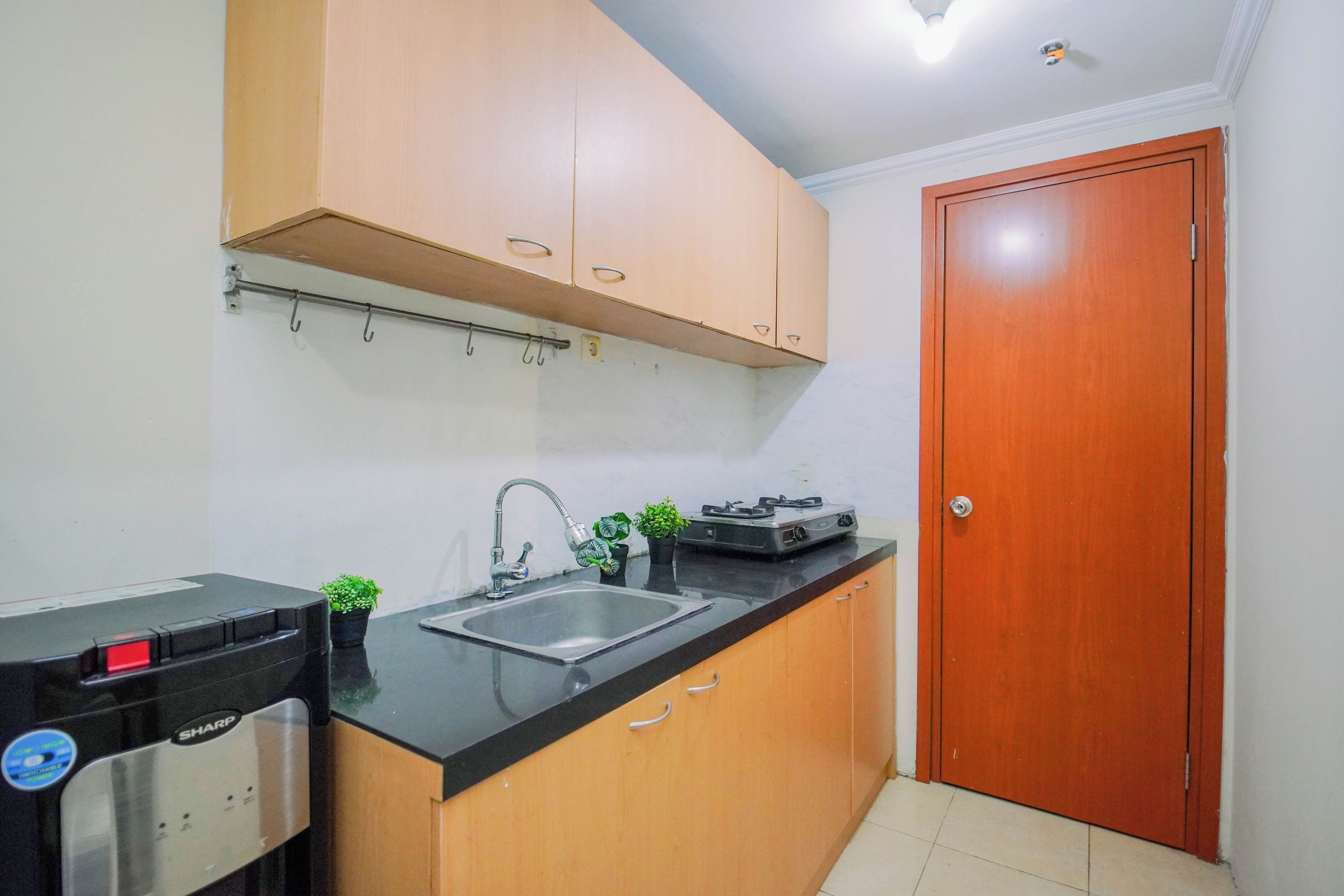 A compact kitchen with a black countertop, a built-in sink, a gas stove, and wooden cabinets.