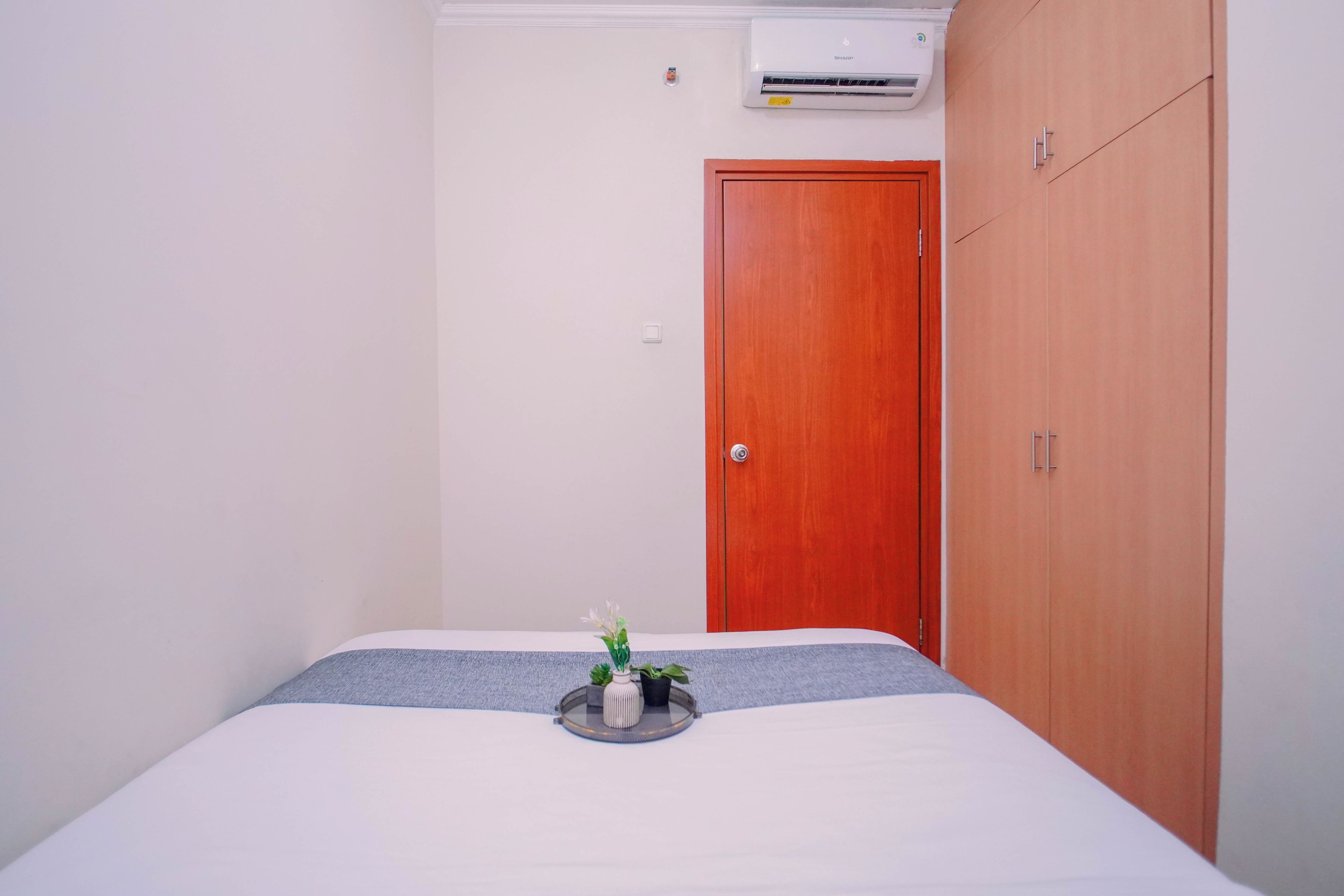Un dormitorio con cama, armario de madera, puerta y aire acondicionado de pared.