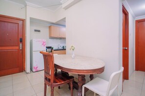 A compact kitchen with a dining table, chairs, and a refrigerator. - Apartment Palazzo/Grand Palace Kemayoran (Jakarta)