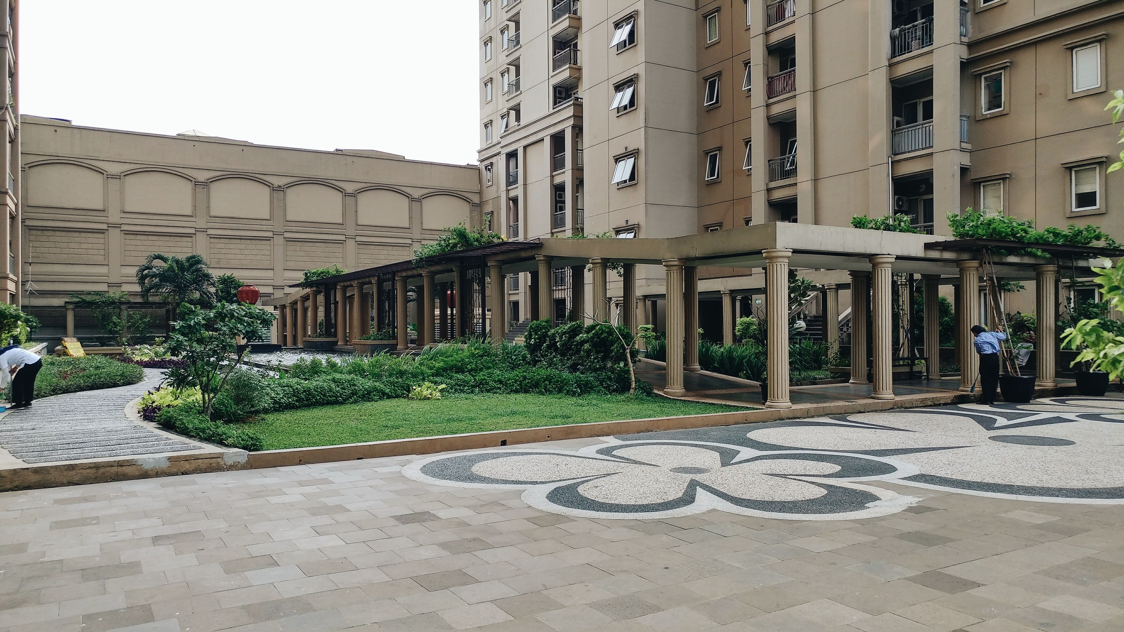 A courtyard with a covered walkway, a fountain, and a building with multiple balconies.