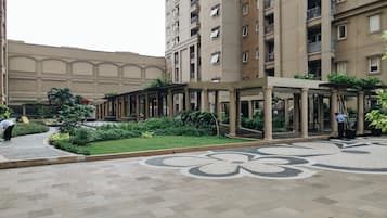 A courtyard with a covered walkway, a fountain, and a building with multiple balconies.