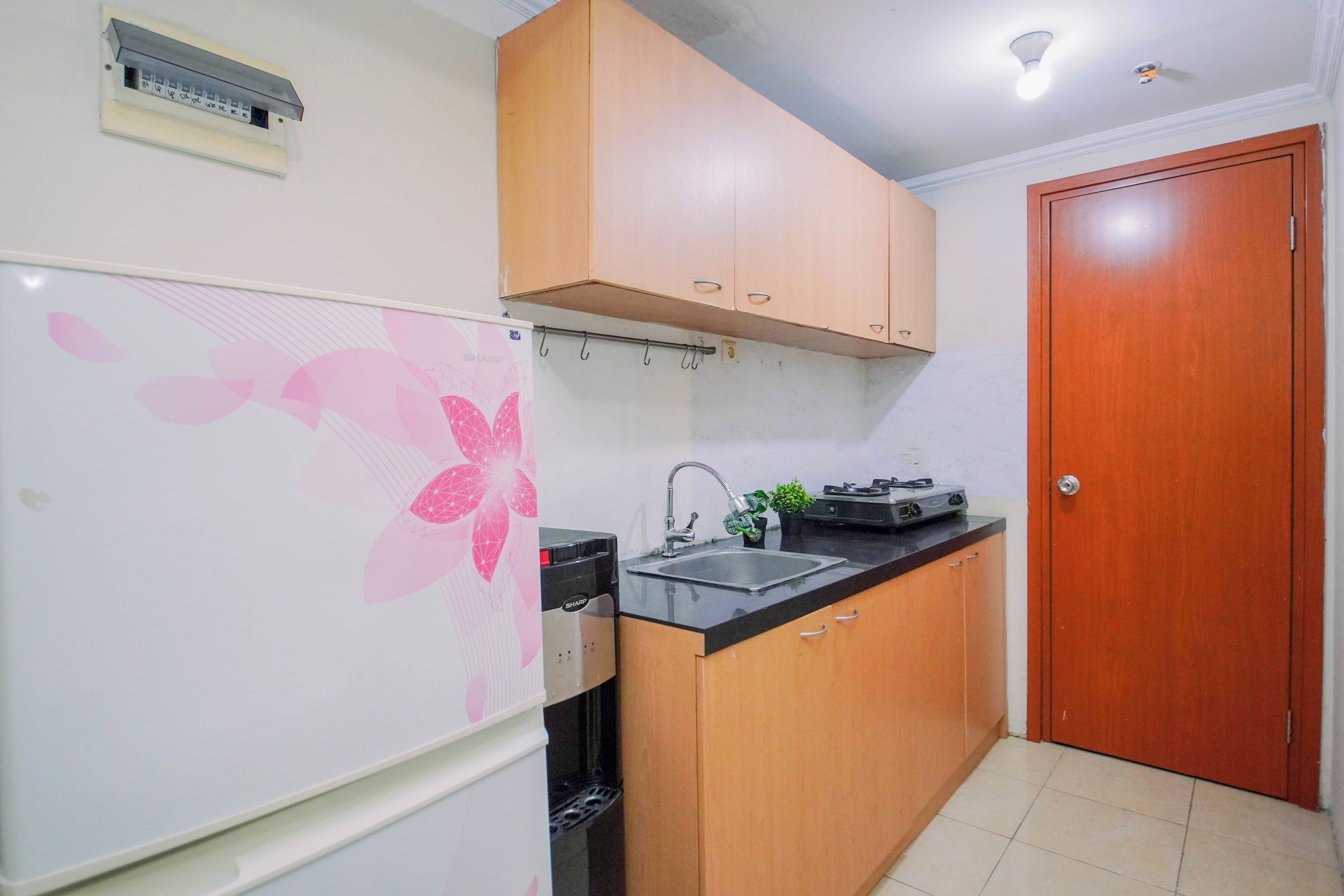 A compact kitchen with a refrigerator, a sink, and wooden cabinets.
