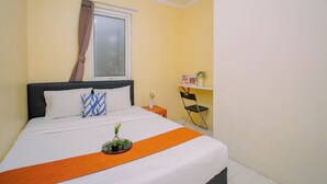 A hotel room with a bed, a window with curtains, a small table with a vase, and a chair. - Apartment Palazzo/Grand Palace Kemayoran (Jakarta)