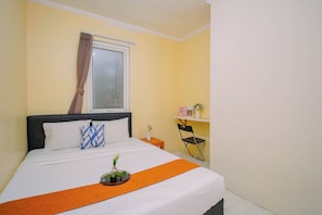 A hotel room with a bed, a window with curtains, a small table with a vase, and a chair. - Apartment Palazzo/Grand Palace Kemayoran (Jakarta)