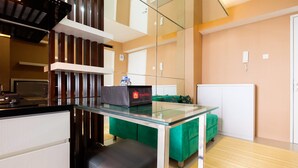 A modern kitchen with a glass-top table, a green sofa, and a minibar. - Luxurious Bassura City Apartment with Mall Access (Jakarta)