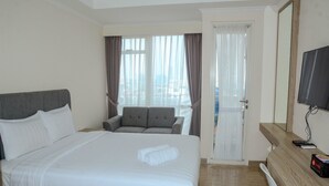 Habitación de hotel con una cama grande, un sofá, un televisor y vistas a la ciudad desde la ventana.
