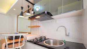 A modern kitchen with a gas stove, stainless steel sink, and pendant lighting. - Compact Bassura City Apartment near Jatinegara (Jakarta)