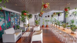 Een moderne lounge met witte meubels, een lange houten tafel en veel potplanten.