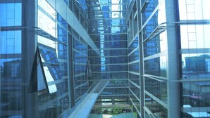Een modern gebouw met meerdere verdiepingen, glazen ramen en een centraal atrium met een gebogen glazen dak.