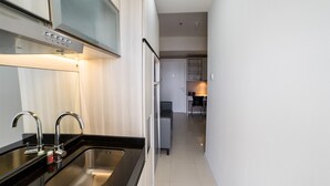 A modern kitchen with stainless steel appliances, a black countertop, and a white backsplash.