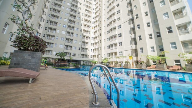 A high-rise residential building with a swimming pool, outdoor seating, and greenery.