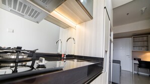 A modern kitchen with a black countertop, stainless steel appliances, and a white backsplash.