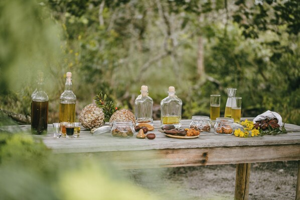 A wooden table set outdoors with various bottles, jars, and food items.