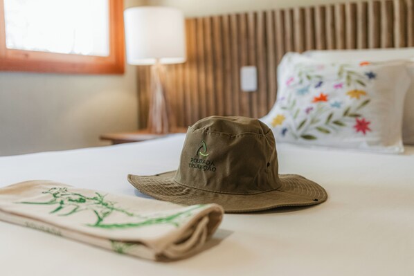 A bed with a brown hat and a folded towel on it.