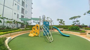 A playground with a slide, climbing structure, and a yellow spiral slide. - Exquisite Bassura City Apartment near Shopping Mall (Jakarta)