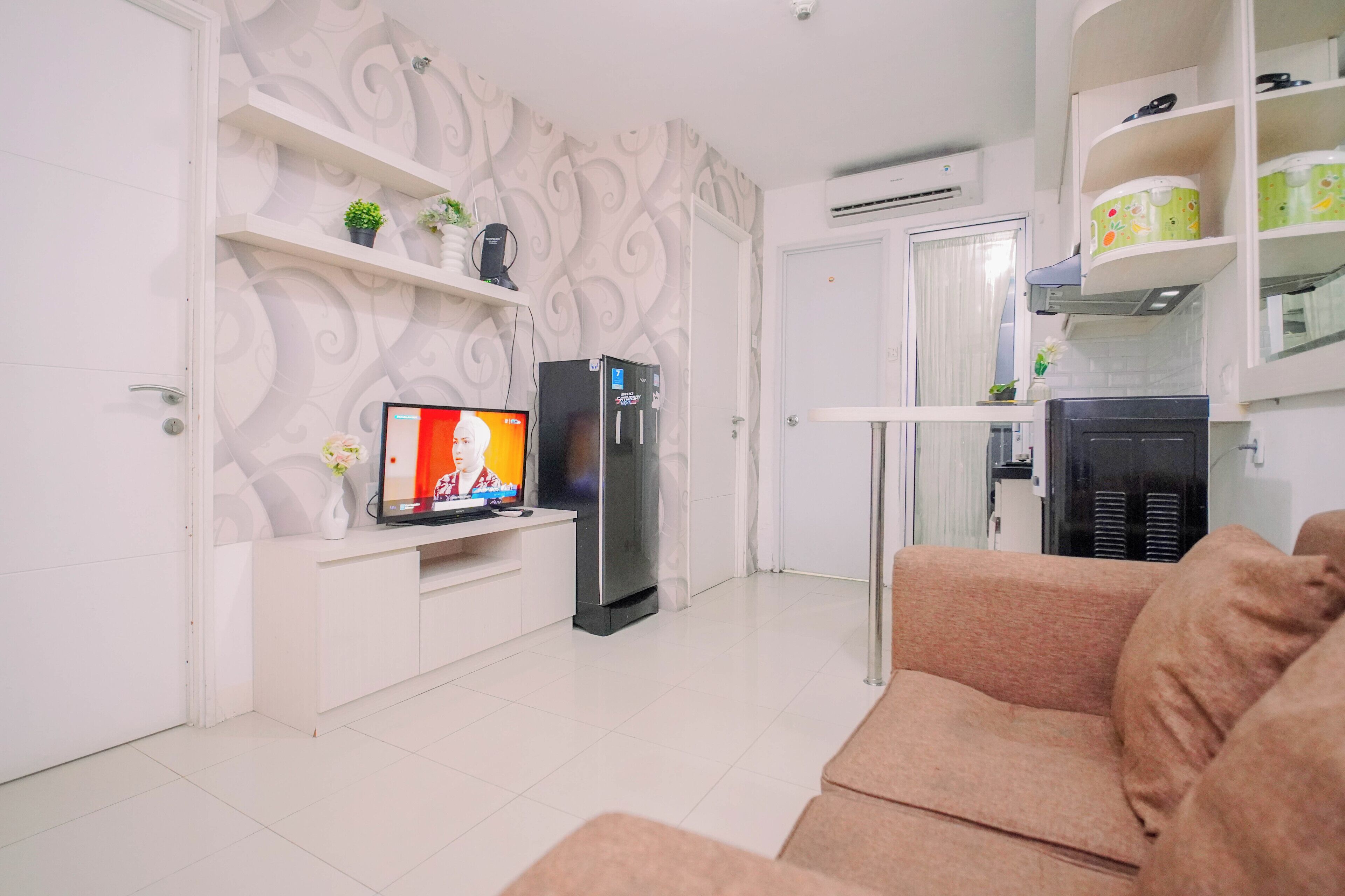 Una sala de estar con televisor, refrigerador y sofá.