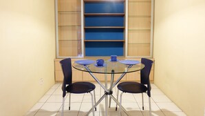 A dining area with a glass table and four chairs, a blue bowl on the table, and a blue shelf unit in the background. - Chrysant Kebagusan City Near Cilandak Mall (Jakarta)