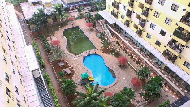 A courtyard with a swimming pool, palm trees, and outdoor seating areas. - Chrysant Kebagusan City Near Cilandak Mall (Jakarta)