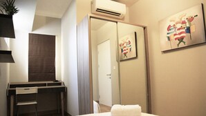 Ein Hotelzimmer mit Bett, Schreibtisch, Stuhl, Kleiderschrank und einem Bild an der Wand.