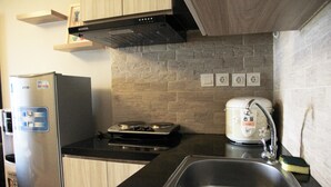Eine kompakte Küche mit einem Edelstahl-Kühlschrank, einem Gasherd, einem Einbauofen, einer Spüle und einem Reiskocher.