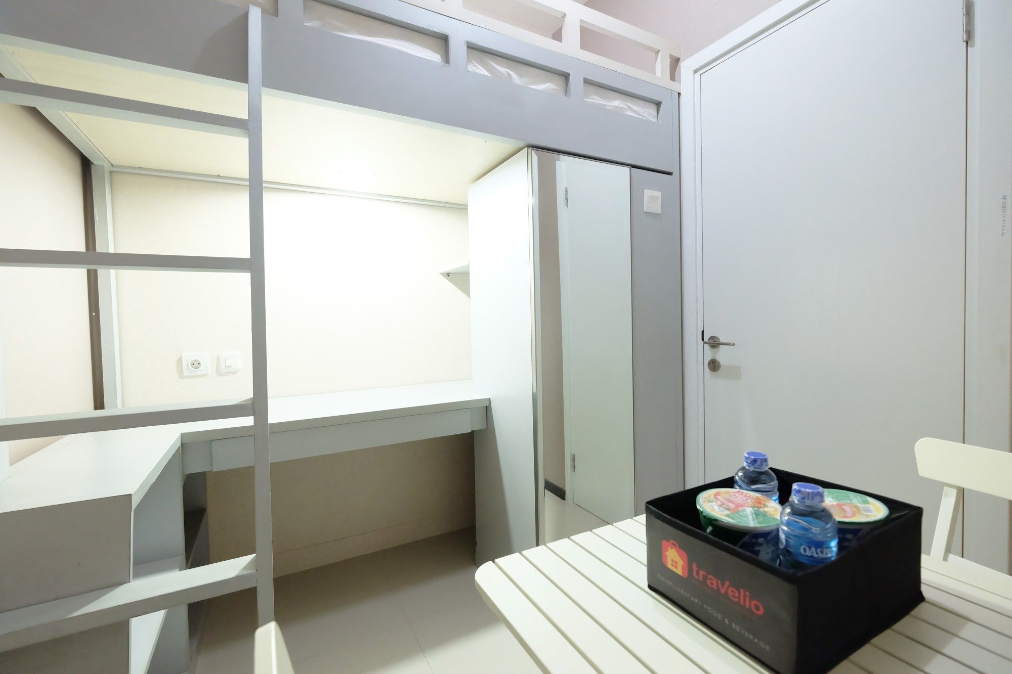 A bunk bed room with a small table, a water dispenser, and a door.