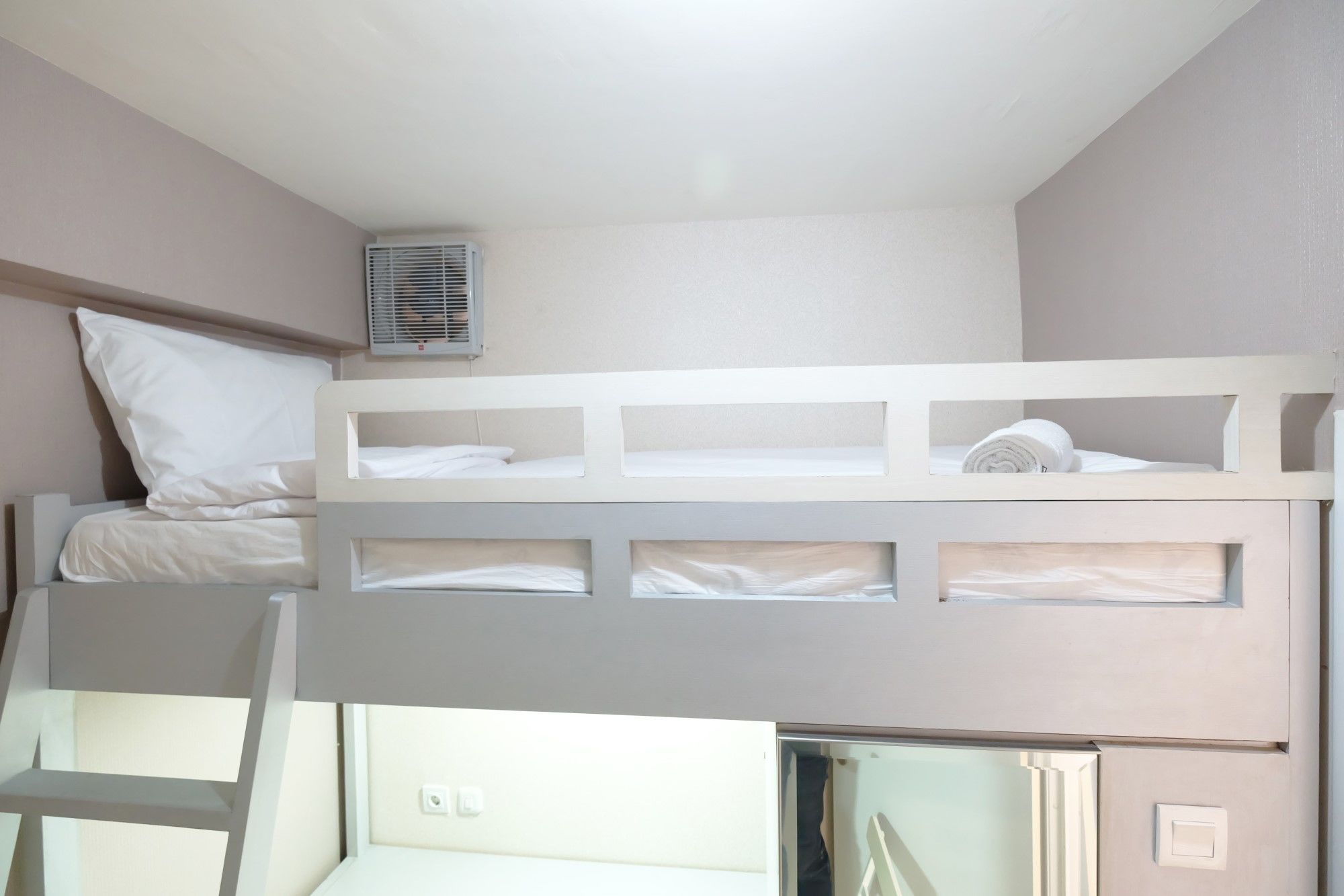 Dormitorio con literas, una escalera, un ventanal pequeño y un equipo de aire acondicionado.