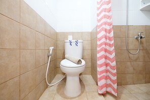 Une salle de bain avec des toilettes, une douche et une serviette posée sur les toilettes.