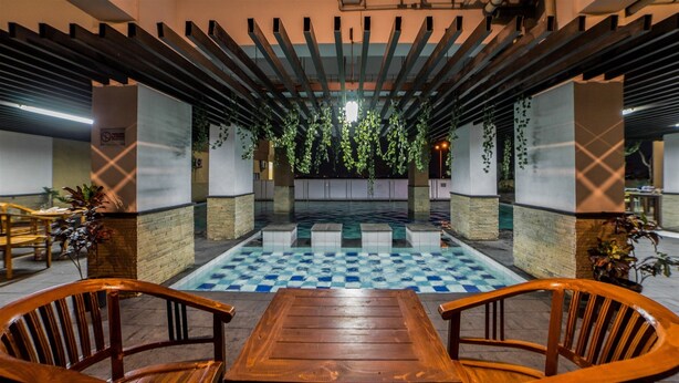 A pool area with a checkered floor, wooden tables and chairs, and hanging plants. - Best Price Tamansari Panoramic Apartment with Mountain View (Bandung)